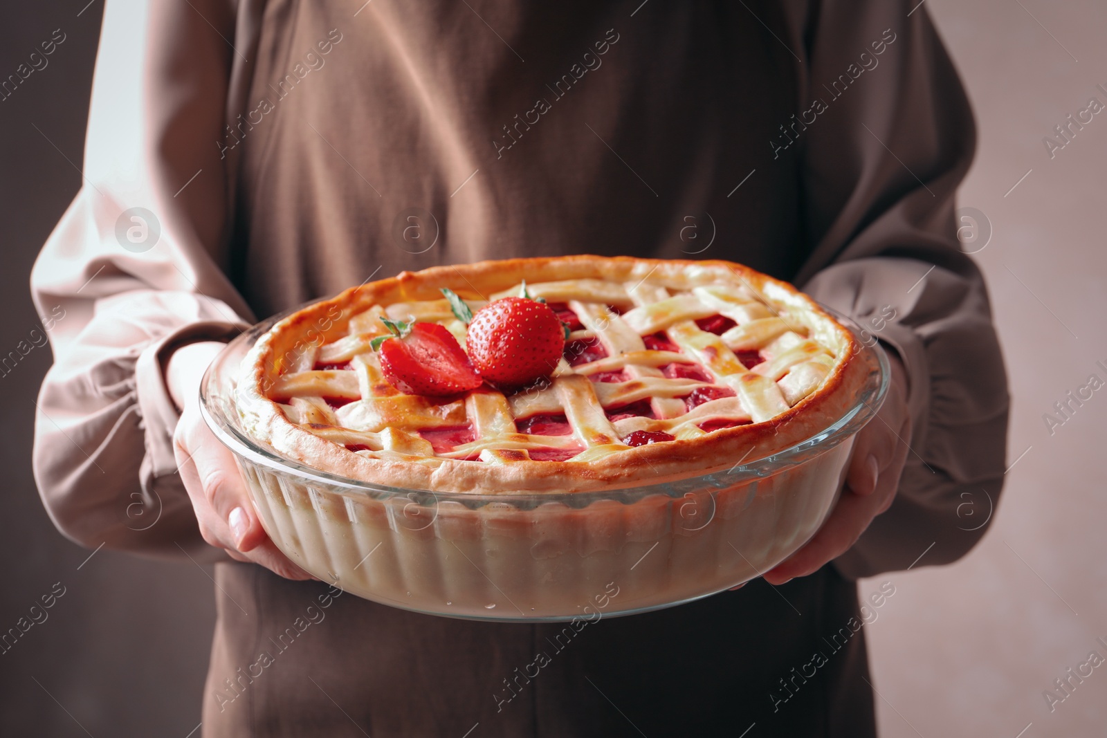 Woman holding tasty strawberry pie on light brown background, closeup Photo of Woman holding tasty strawberry pie on light brown background, closeup