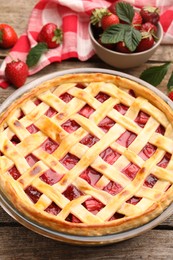 Photo of Tasty strawberry pie and berries on wooden table, closeup