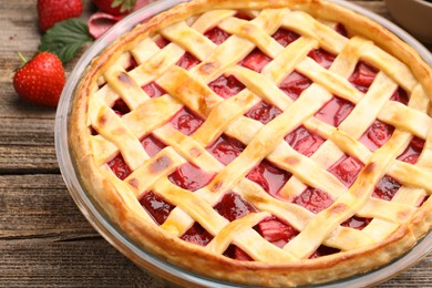Photo of Tasty strawberry pie and berries on wooden table, closeup