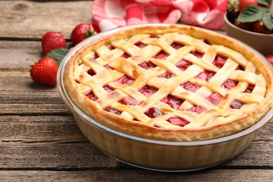Photo of Tasty strawberry pie and berries on wooden table, closeup