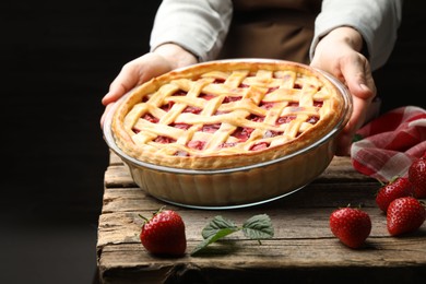 Photo of Woman with tasty strawberry pie at wooden table, closeup