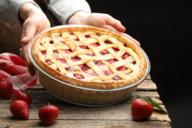 Photo of Woman with tasty strawberry pie at wooden table, closeup