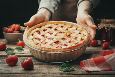 Photo of Woman with tasty strawberry pie at wooden table, closeup