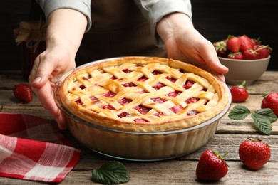 Photo of Woman with tasty strawberry pie at wooden table, closeup