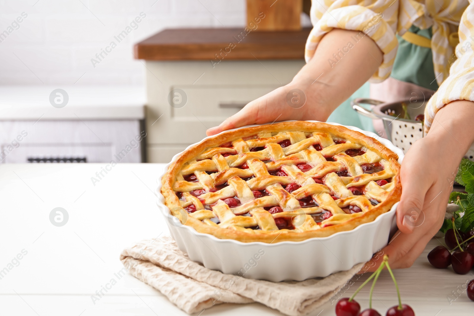 Photo of Woman with tasty cherry pie at white wooden table, closeup. Space for text