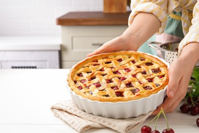 Photo of Woman with tasty cherry pie at white wooden table, closeup. Space for text