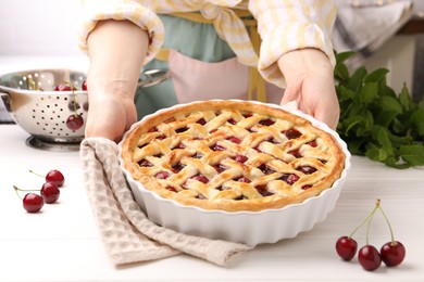 Photo of Woman with tasty cherry pie at white wooden table, closeup