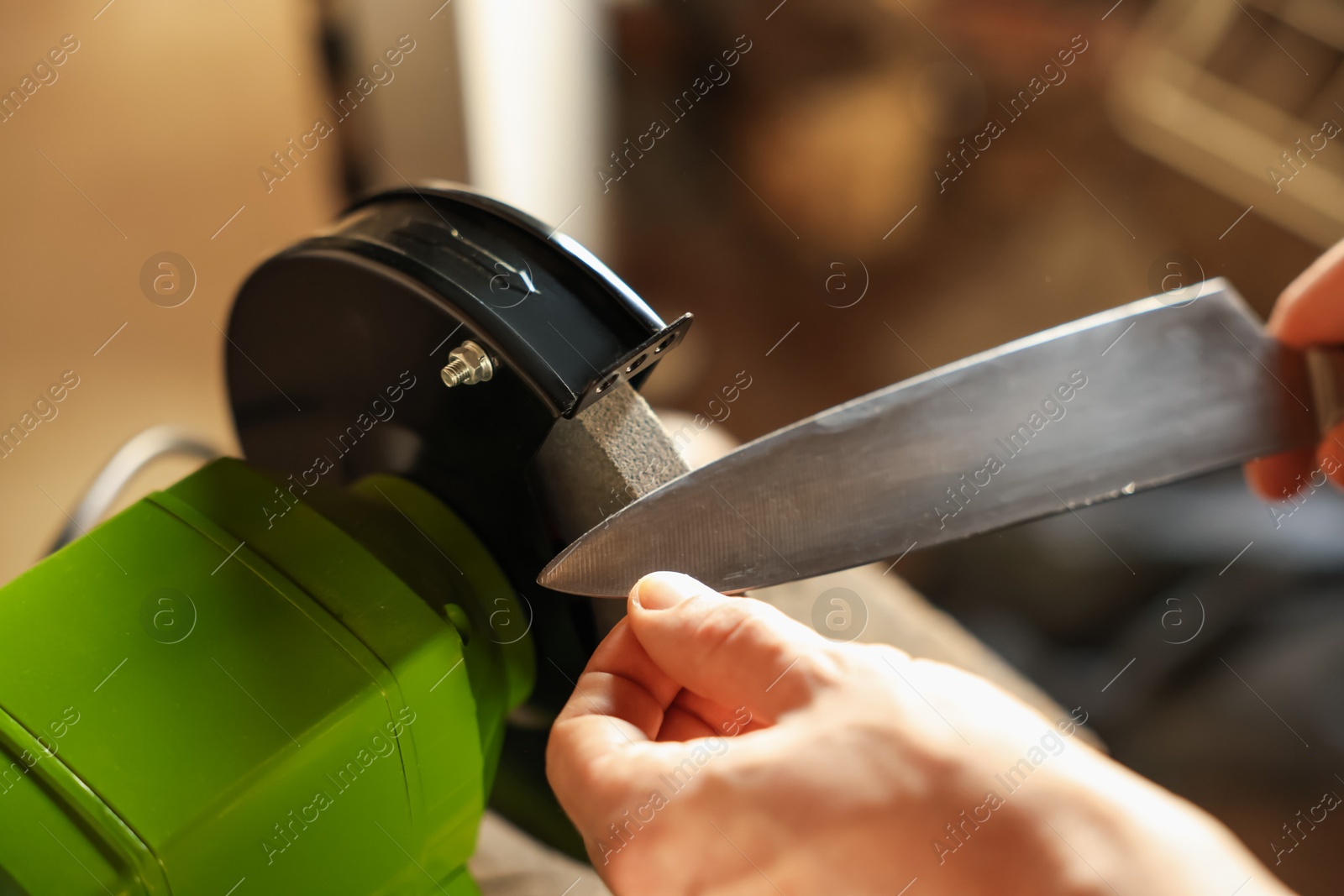 Man sharpening knife with bench grinder indoors, above view Photo of Man sharpening knife with bench grinder indoors, above view