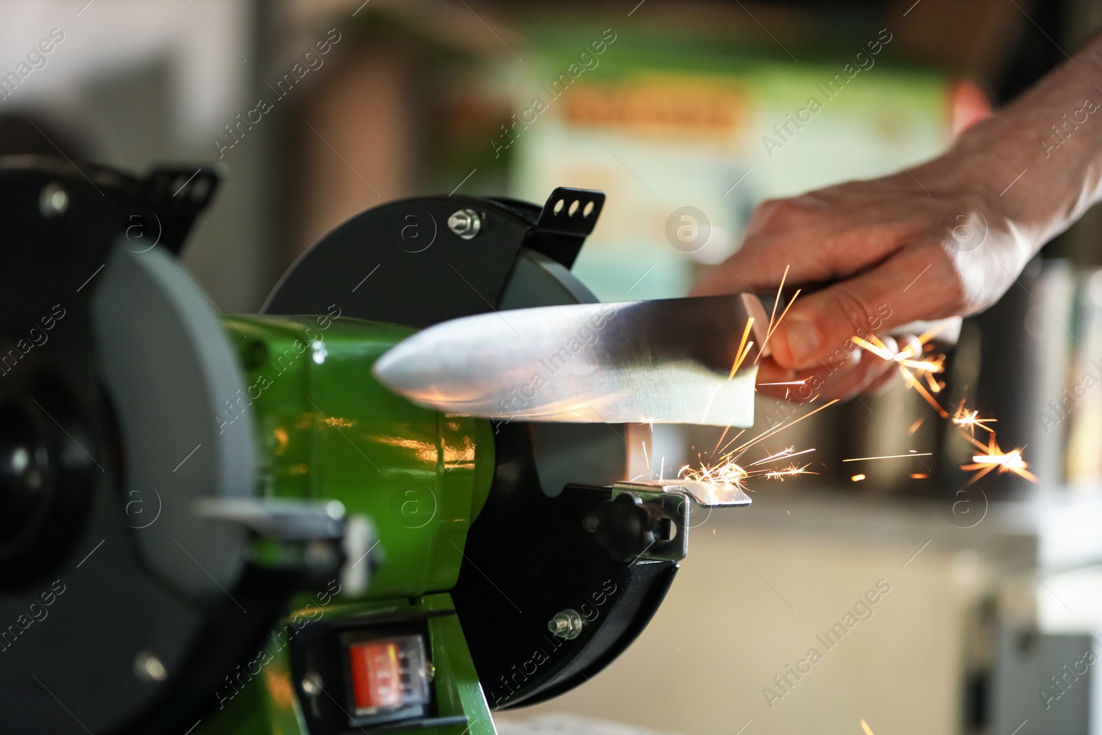 Man sharpening knife with bench grinder indoors, closeup Photo of Man sharpening knife with bench grinder indoors, closeup