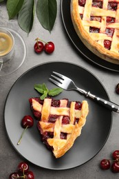 Photo of Piece of tasty cherry pie and berries on grey table, flat lay