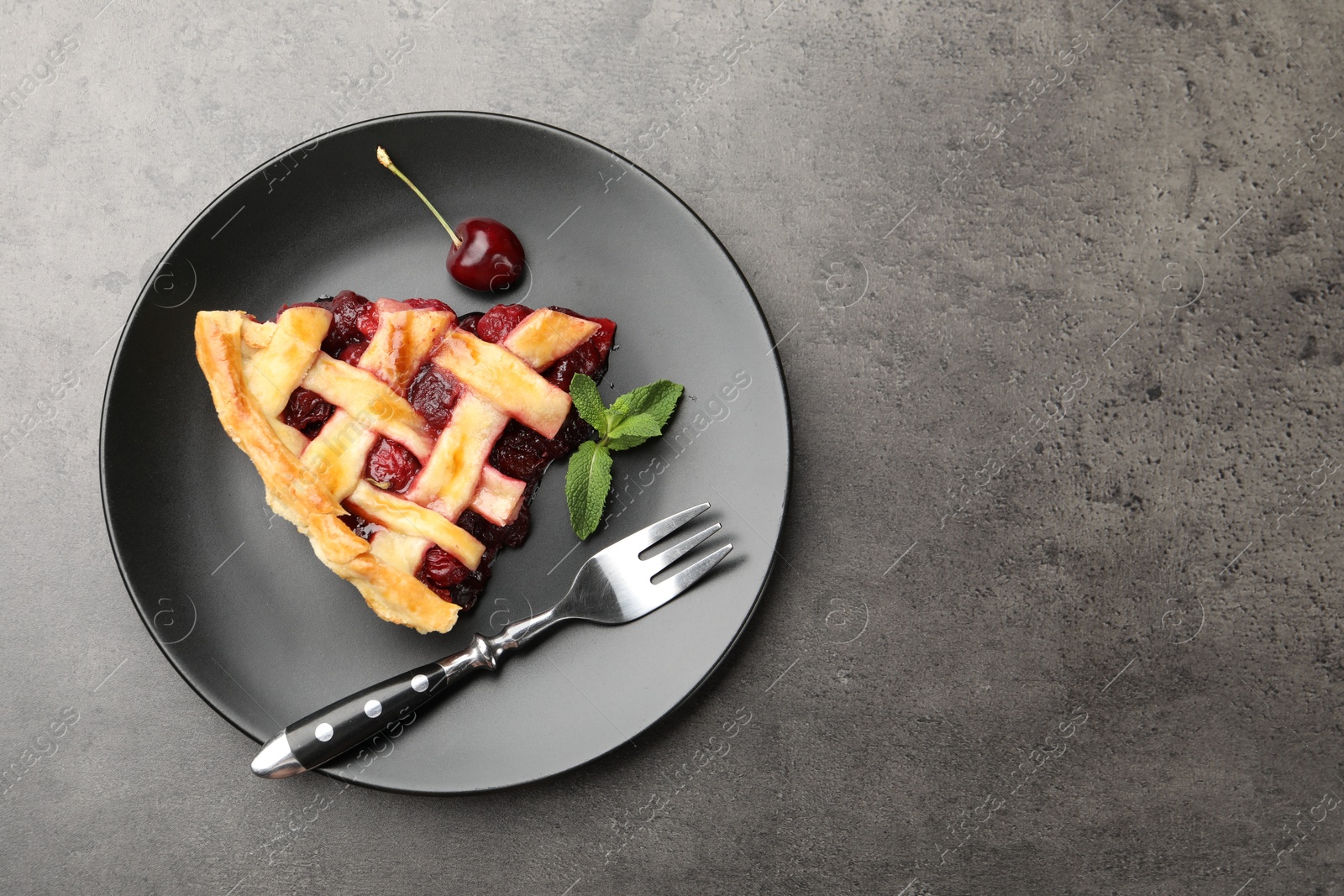 Photo of Piece of tasty cherry pie on grey table, top view. Space for text