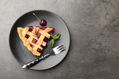 Photo of Piece of tasty cherry pie on grey table, top view. Space for text