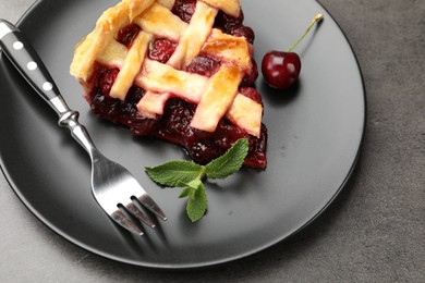 Photo of Piece of tasty cherry pie and berries on grey table, closeup