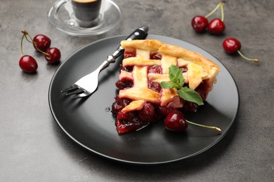 Photo of Piece of tasty cherry pie and berries on grey table, closeup