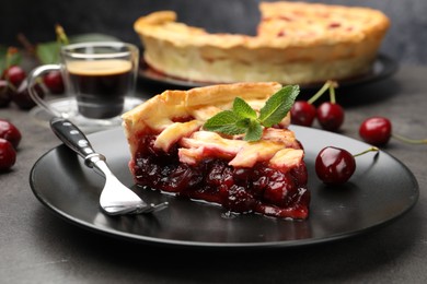 Photo of Piece of tasty cherry pie and berries on grey table, closeup