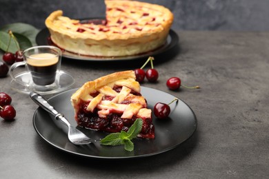 Photo of Piece of tasty cherry pie and berries on grey table, closeup