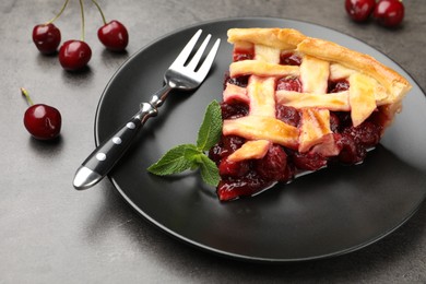 Photo of Piece of tasty cherry pie and berries on grey table, closeup