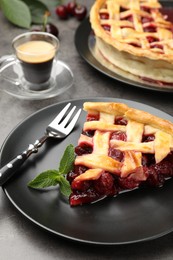 Photo of Piece of tasty cherry pie and berries on grey table, closeup