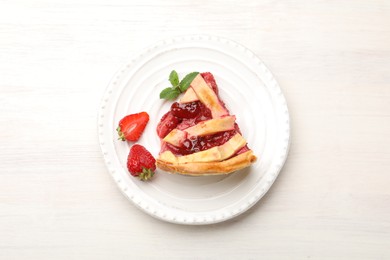 Photo of Piece of tasty strawberry pie and berries on white wooden table, top view