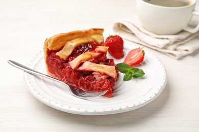 Photo of Piece of tasty strawberry pie and berries on white wooden table, closeup