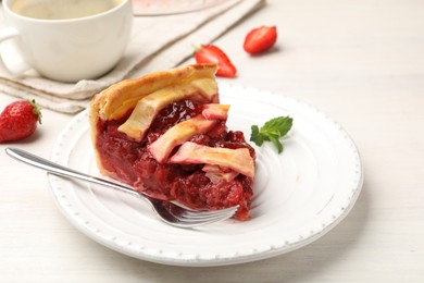 Photo of Piece of tasty strawberry pie and berries on white wooden table, closeup