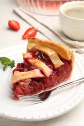 Photo of Piece of tasty strawberry pie and berries on white wooden table, closeup
