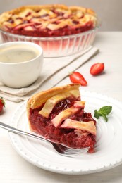 Photo of Piece of tasty strawberry pie and berries on white wooden table, closeup