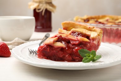 Photo of Piece of tasty strawberry pie and berries on white wooden table, closeup