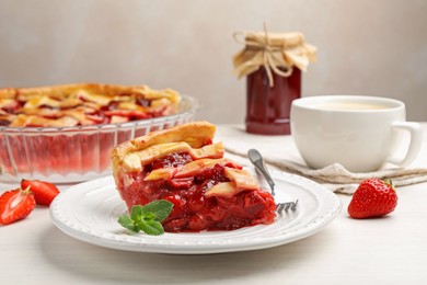 Photo of Piece of tasty strawberry pie and berries on white wooden table, closeup