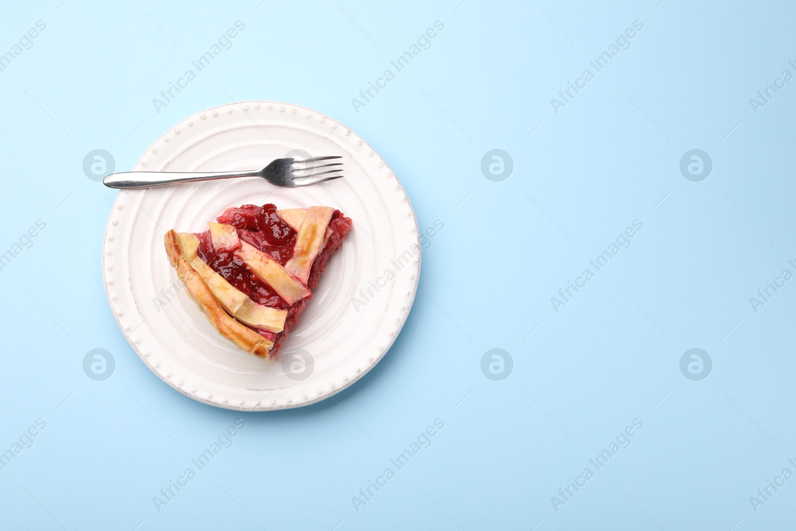 Piece of tasty strawberry pie on light blue background, top view. Space for text Photo of Piece of tasty strawberry pie on light blue background, top view. Space for text