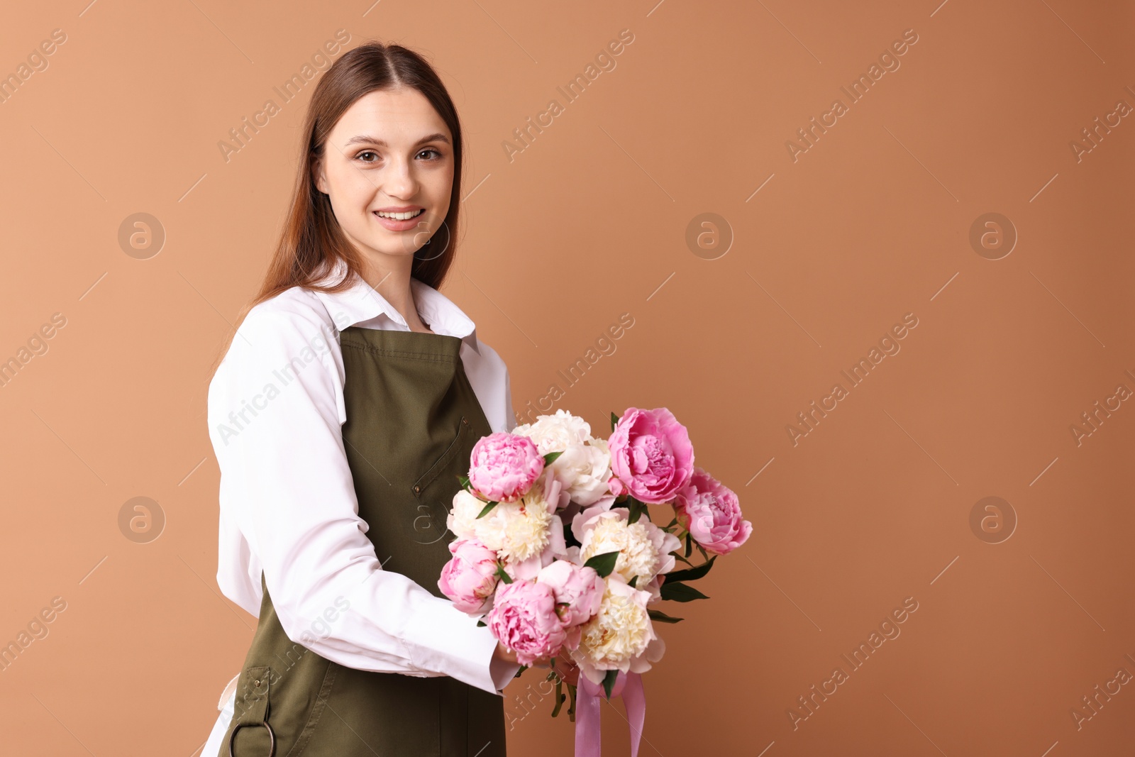 Florist with beautiful bouquet of peonies on dark beige background, space for text Photo of Florist with beautiful bouquet of peonies on dark beige background, space for text