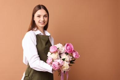 Photo of Florist with beautiful bouquet of peonies on dark beige background, space for text