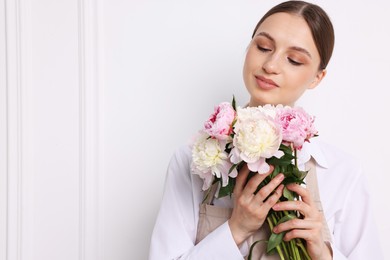 Photo of Florist with beautiful bouquet of peonies near white wall indoors, space for text