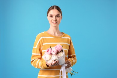 Photo of Woman with beautiful bouquet of peonies on light blue background