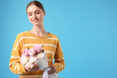 Photo of Woman with beautiful bouquet of peonies on light blue background, space for text