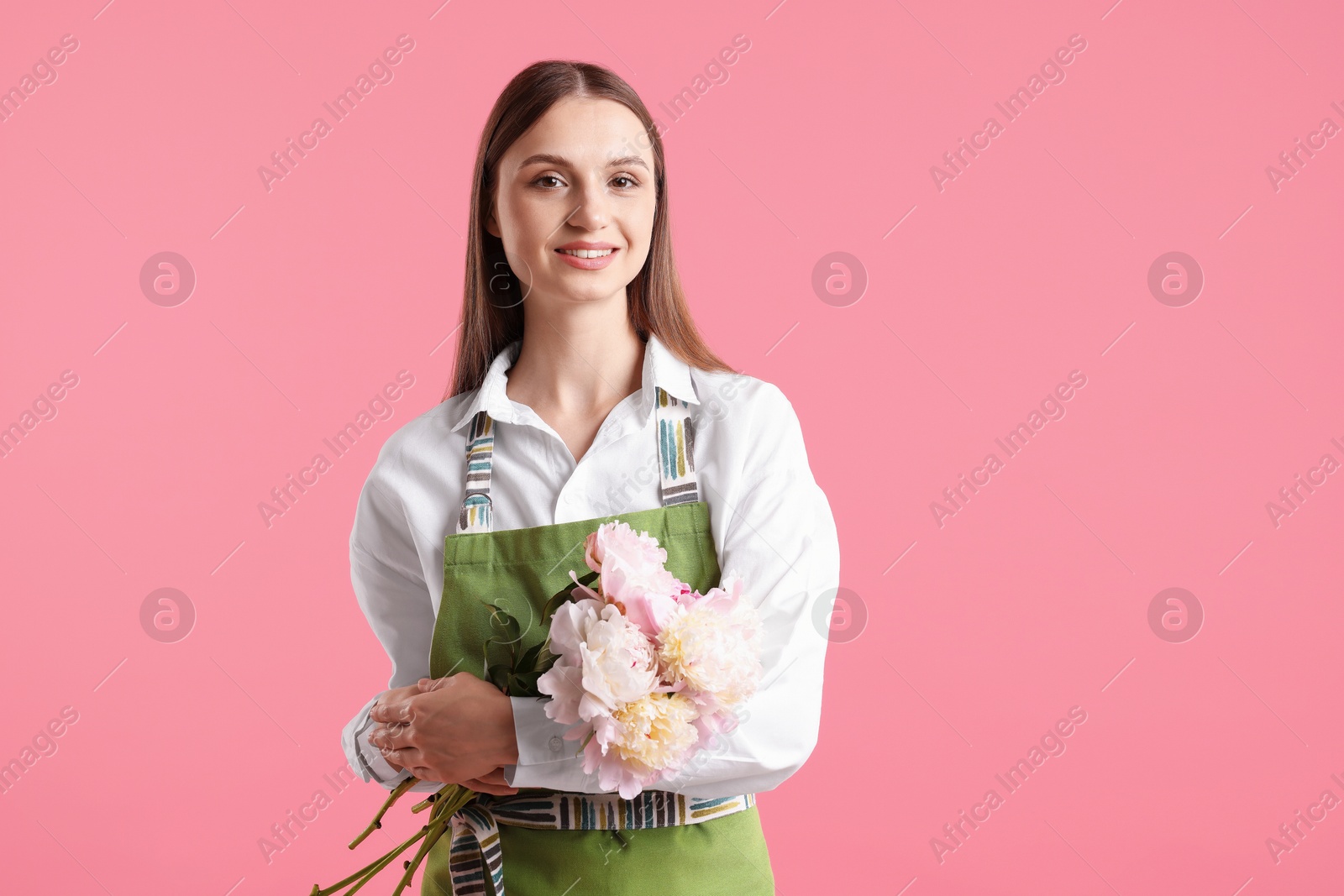Florist with beautiful peonies on pink background Photo of Florist with beautiful peonies on pink background