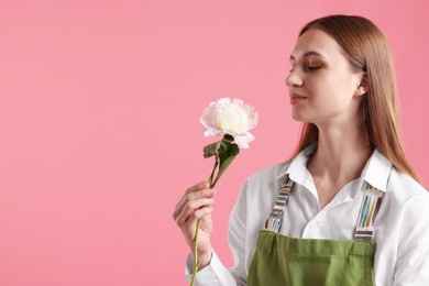 Photo of Florist with beautiful peony on pink background, space for text