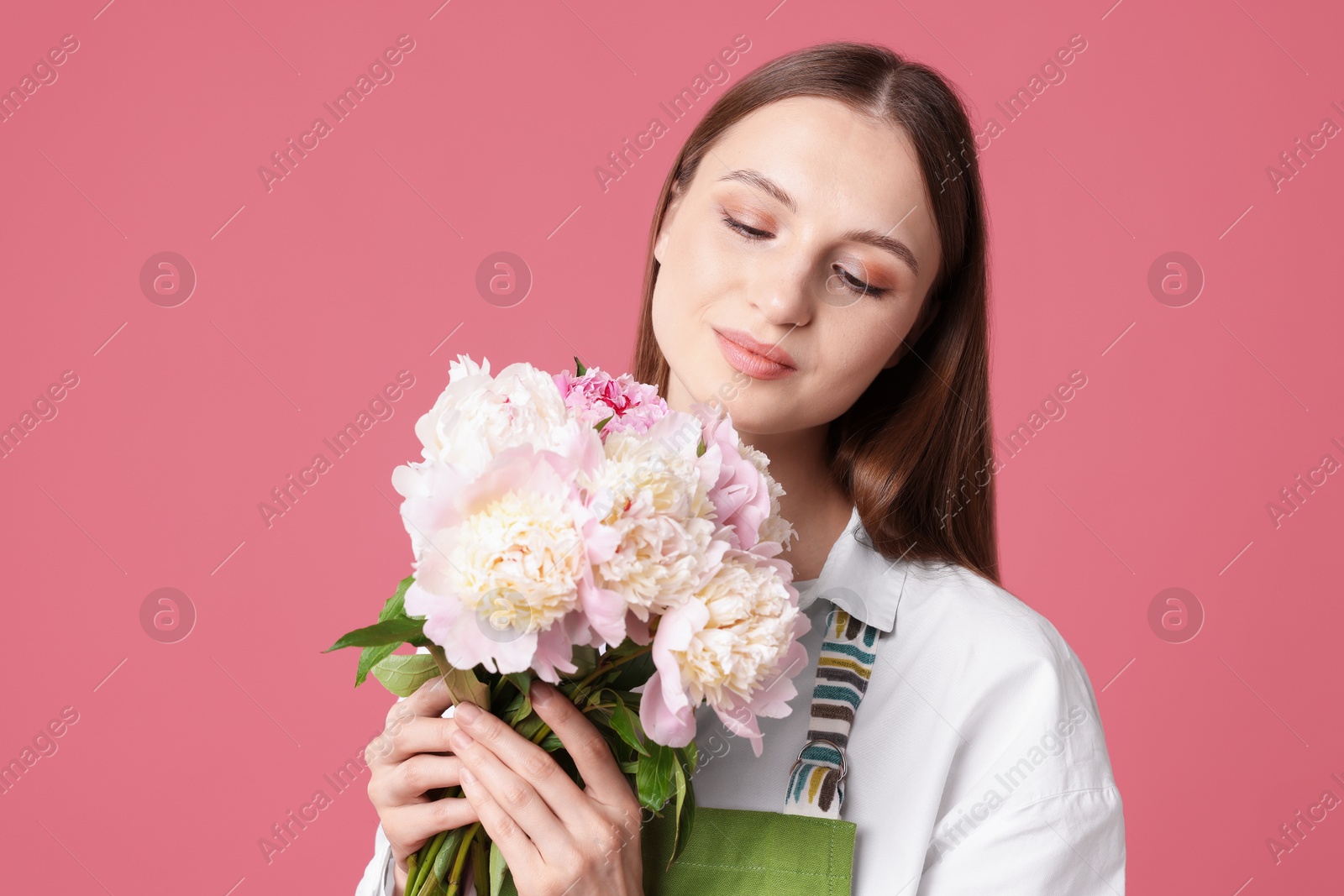 Florist with beautiful peonies on pink background Photo of Florist with beautiful peonies on pink background