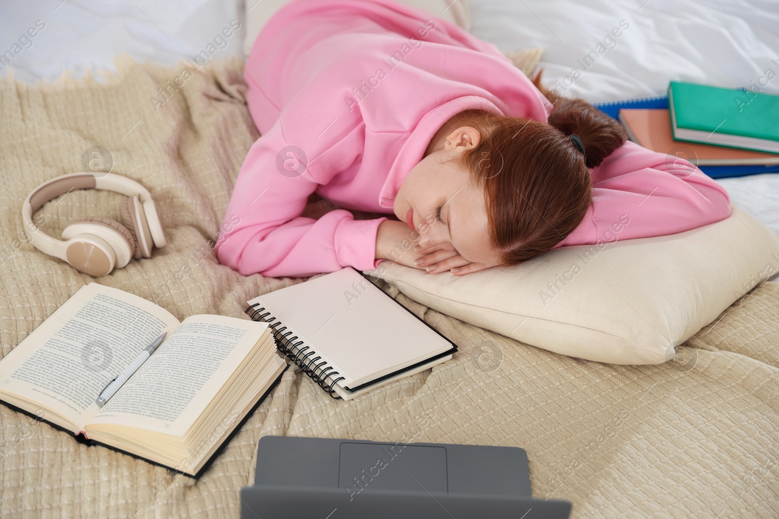 Tired teenage student sleeping near books and laptop on bed at home, above view Photo of Tired teenage student sleeping near books and laptop on bed at home, above view