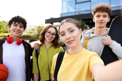 Photo of Group of happy teenagers taking selfie outdoors