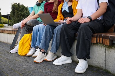 Photo of Teenagers with laptop on bench in park, closeup