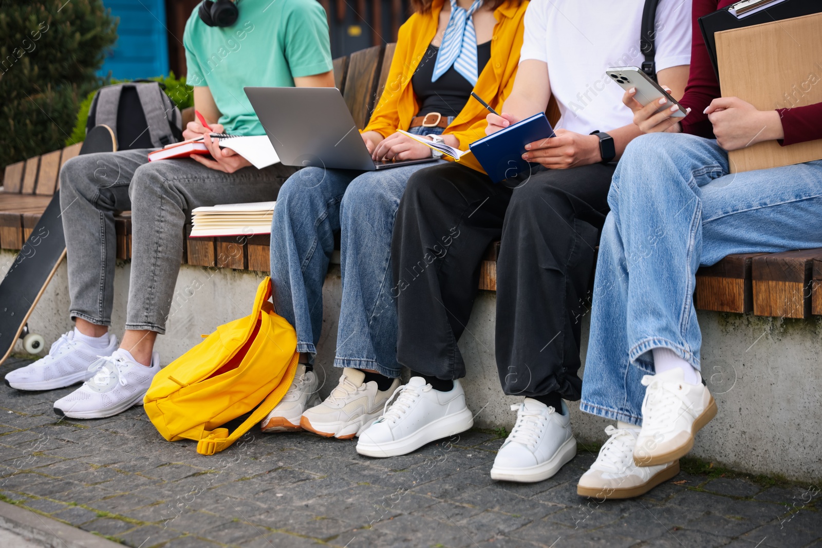 Teenagers studying together on bench outdoors, closeup Photo of Teenagers studying together on bench outdoors, closeup