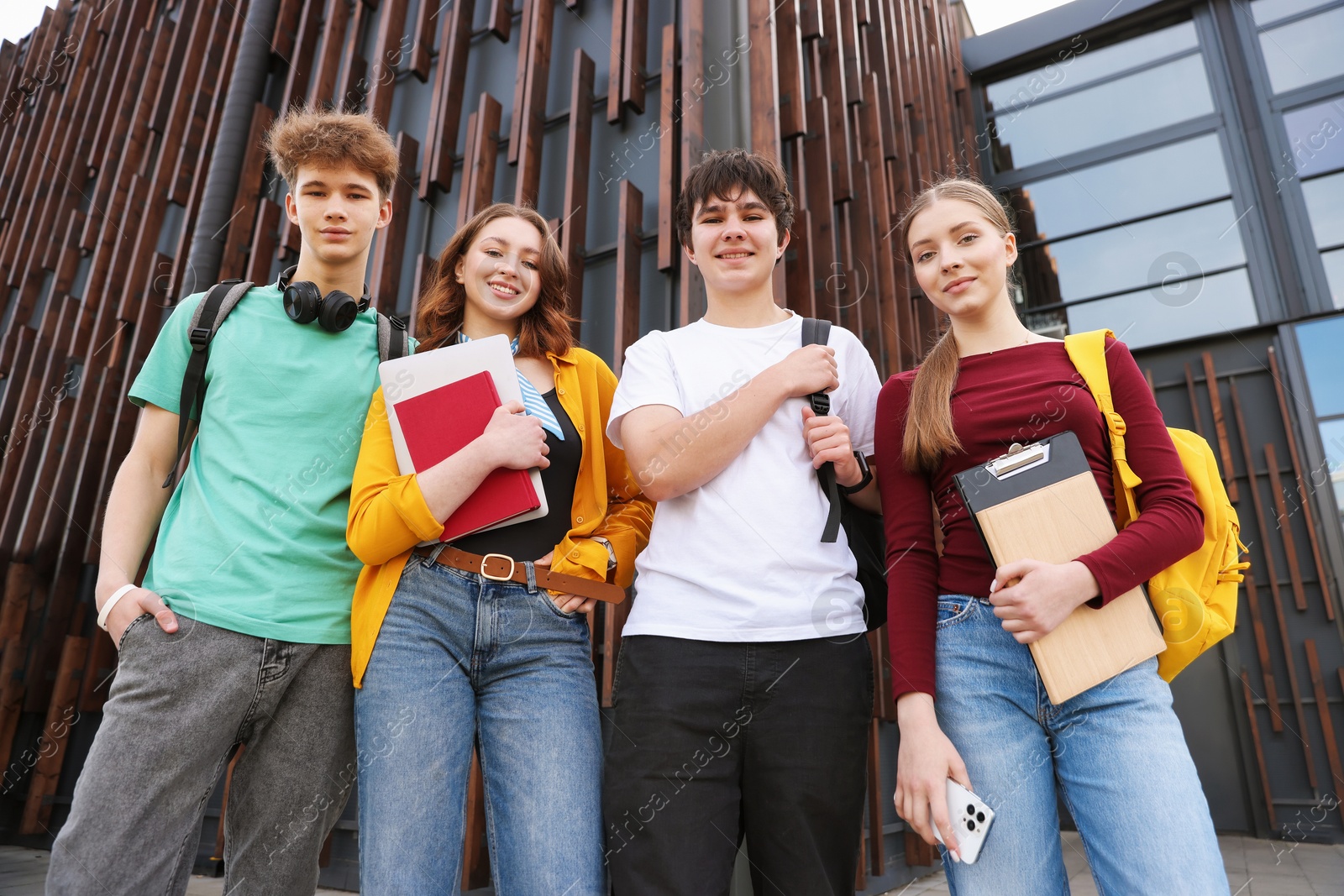 Group of happy teenagers near building outdoors, low angle view Photo of Group of happy teenagers near building outdoors, low angle view