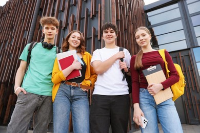 Photo of Group of happy teenagers near building outdoors, low angle view