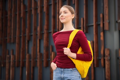Photo of Teenage girl with backpack near building outdoors, space for text
