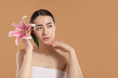 Photo of Beautiful woman after spa treatment with lily flower on beige background. Space for text