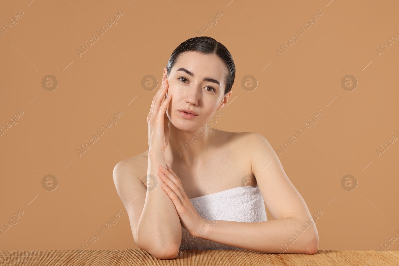 Beautiful woman after spa treatment at bamboo table on beige background Photo of Beautiful woman after spa treatment at bamboo table on beige background