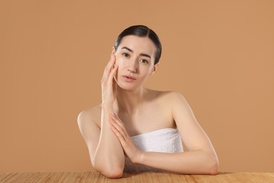 Photo of Beautiful woman after spa treatment at bamboo table on beige background
