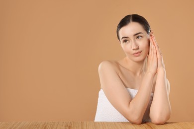 Photo of Beautiful woman after spa treatment at bamboo table on beige background. Space for text