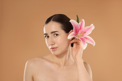 Photo of Portrait of beautiful woman after spa treatment with lily flower on beige background